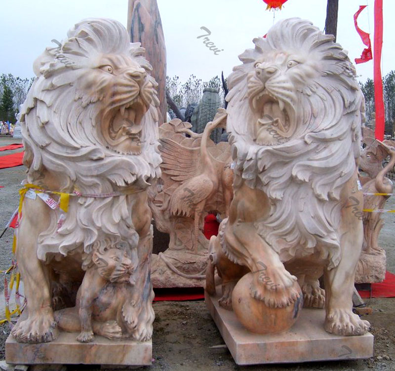 Pair of guardian sitting lions statue with ball in front of house