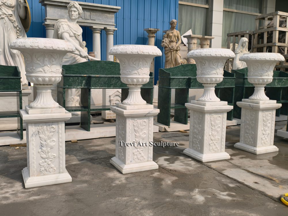 a set of classical white marble urn planters with matching floral relief pedestals