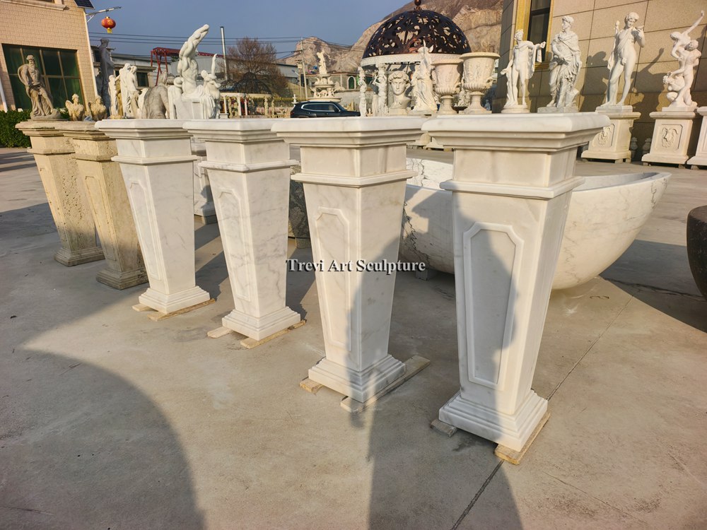 sleek and modern tapered white marble display plinths with subtle carved paneling