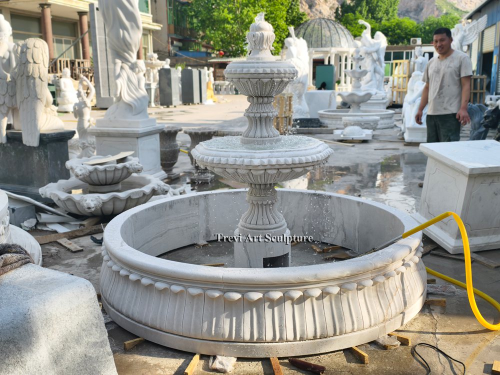 tiered white marble water fountain with a carved basin base during water testing